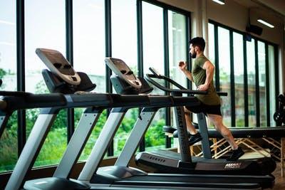 Man Running on treadmill in the Gym trying to lose fat, lose weight.